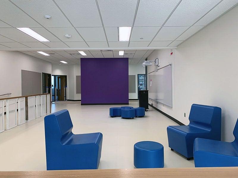 团体区域设有座椅群, 学习之墙, and a teacher station with a purple wall separating it from the hallway